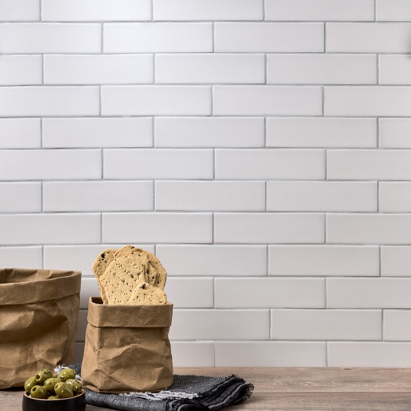 Wall of sky white skinny metro matt tiles with silver grey grout styled with kitchen accessories